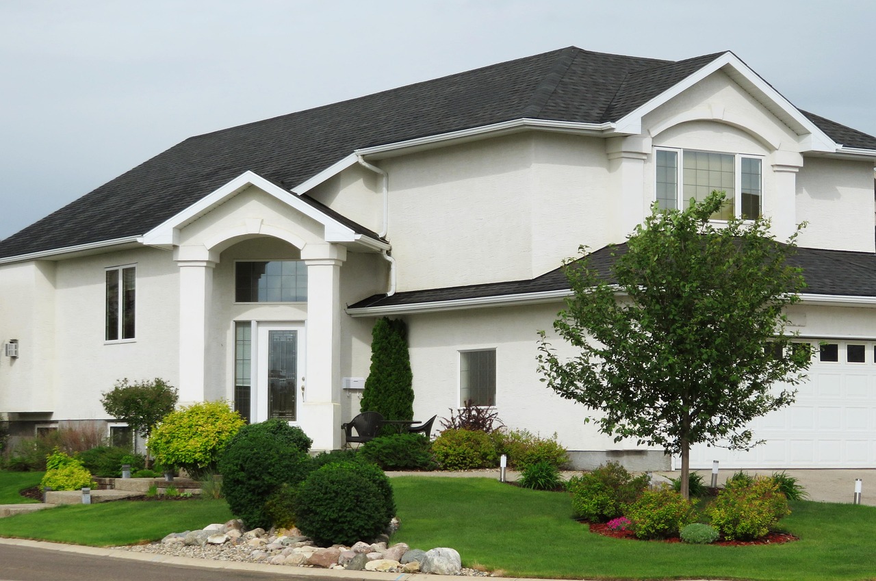 Stucco home with a trimmed lawn and shrub beds out front